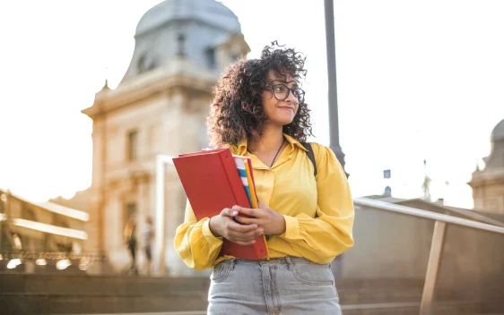 student standing with book in hand